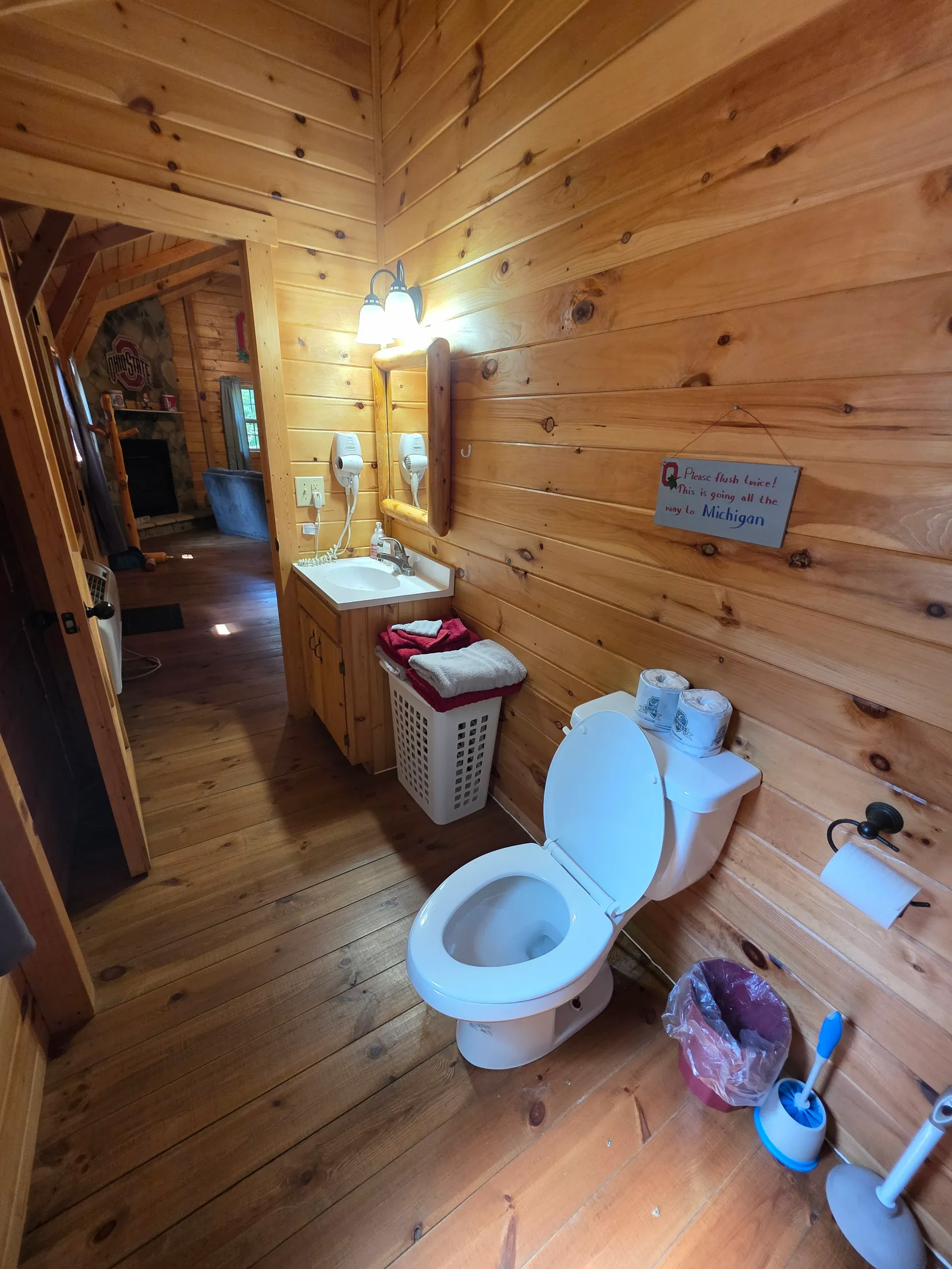 Pine-paneled bathroom with toilet and vanity at Buckeye Hut cabin