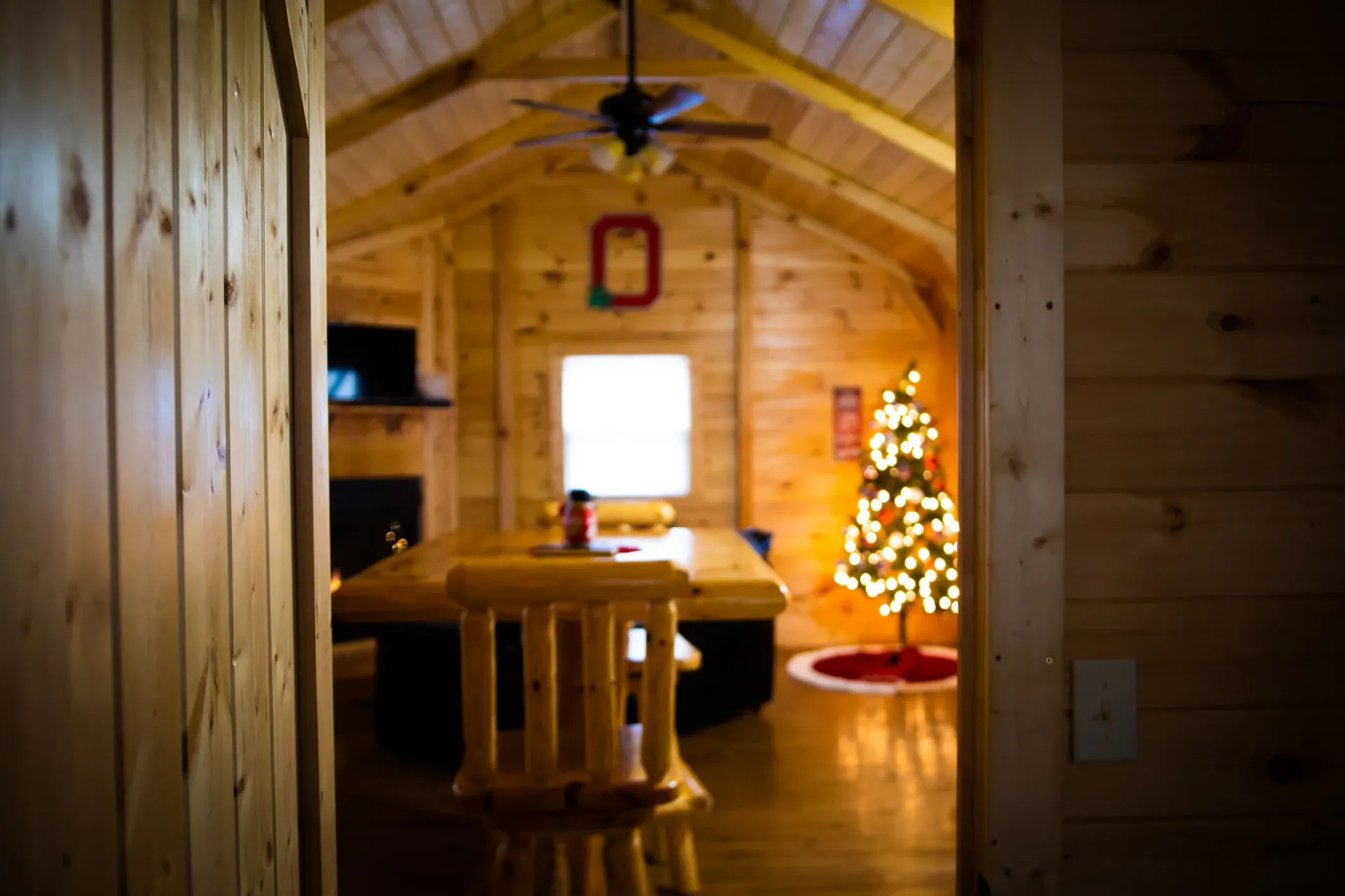 Warm interior of Buckeye Hut cabin with Christmas tree, log table, and pine-paneled walls