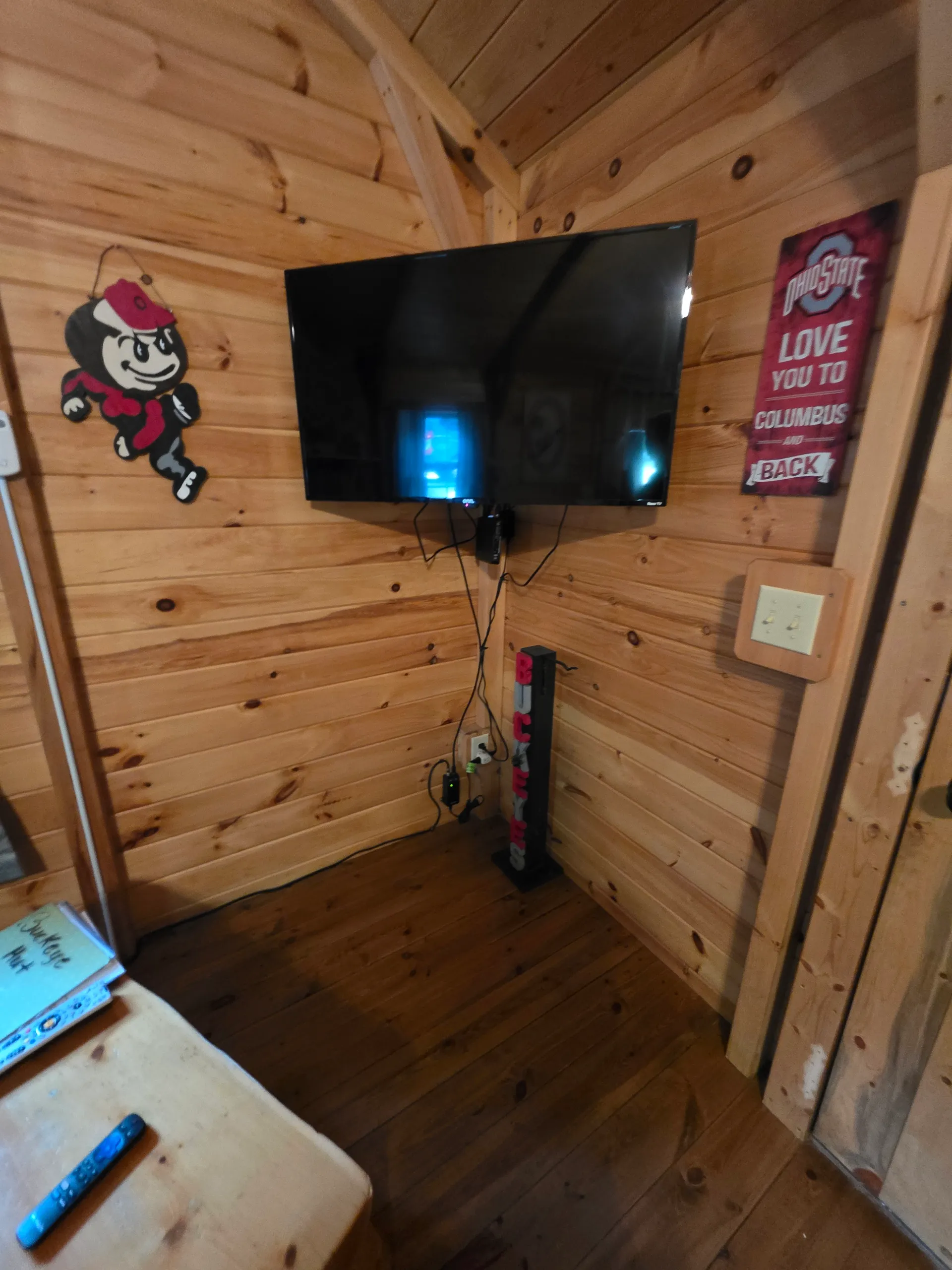 Entertainment area with wall-mounted TV, soundbar, and Ohio State decor at Buckeye Hut cabin