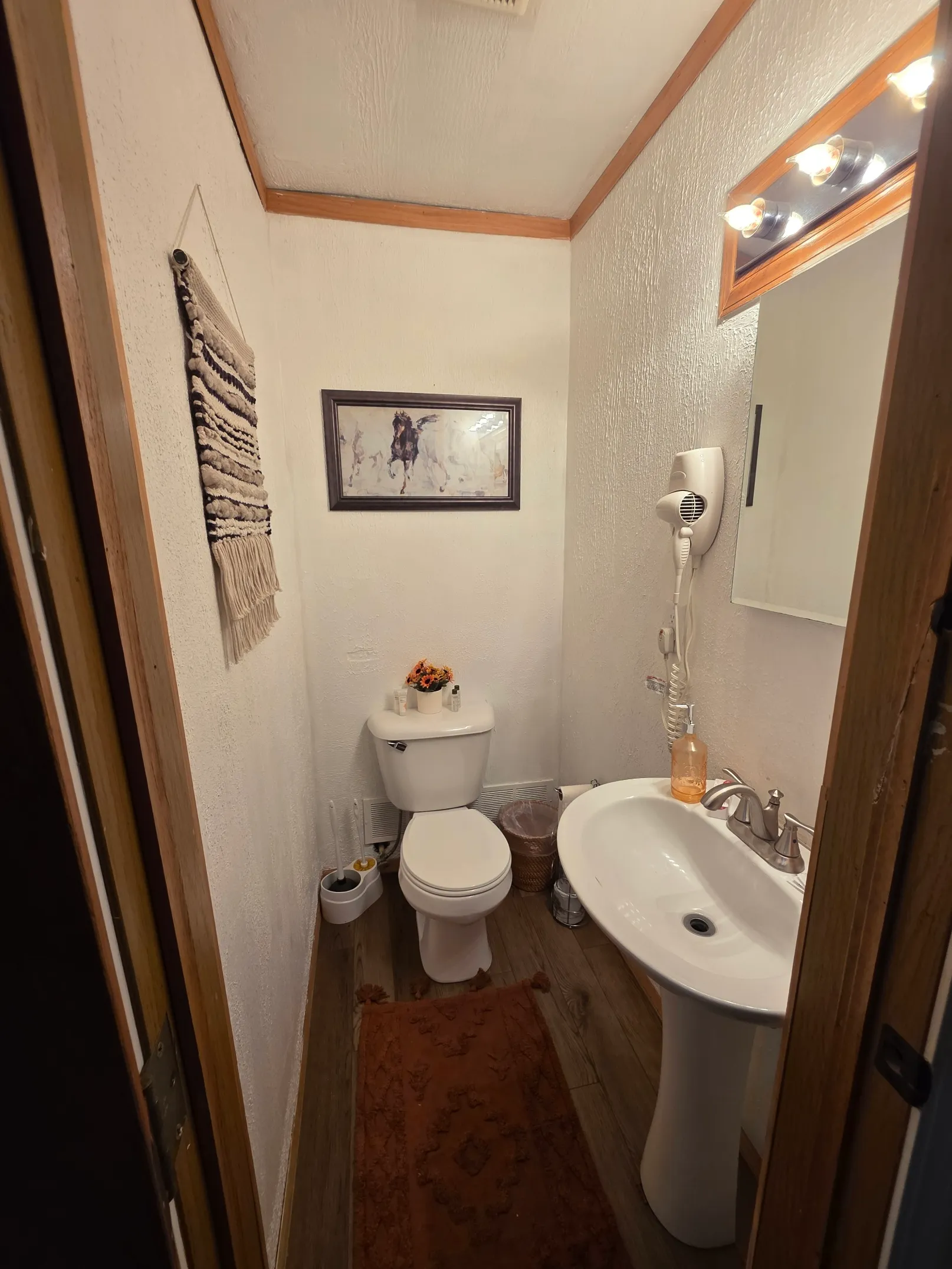 Bathroom with pedestal sink, framed artwork, and woven rug at Cherokee Way cabin