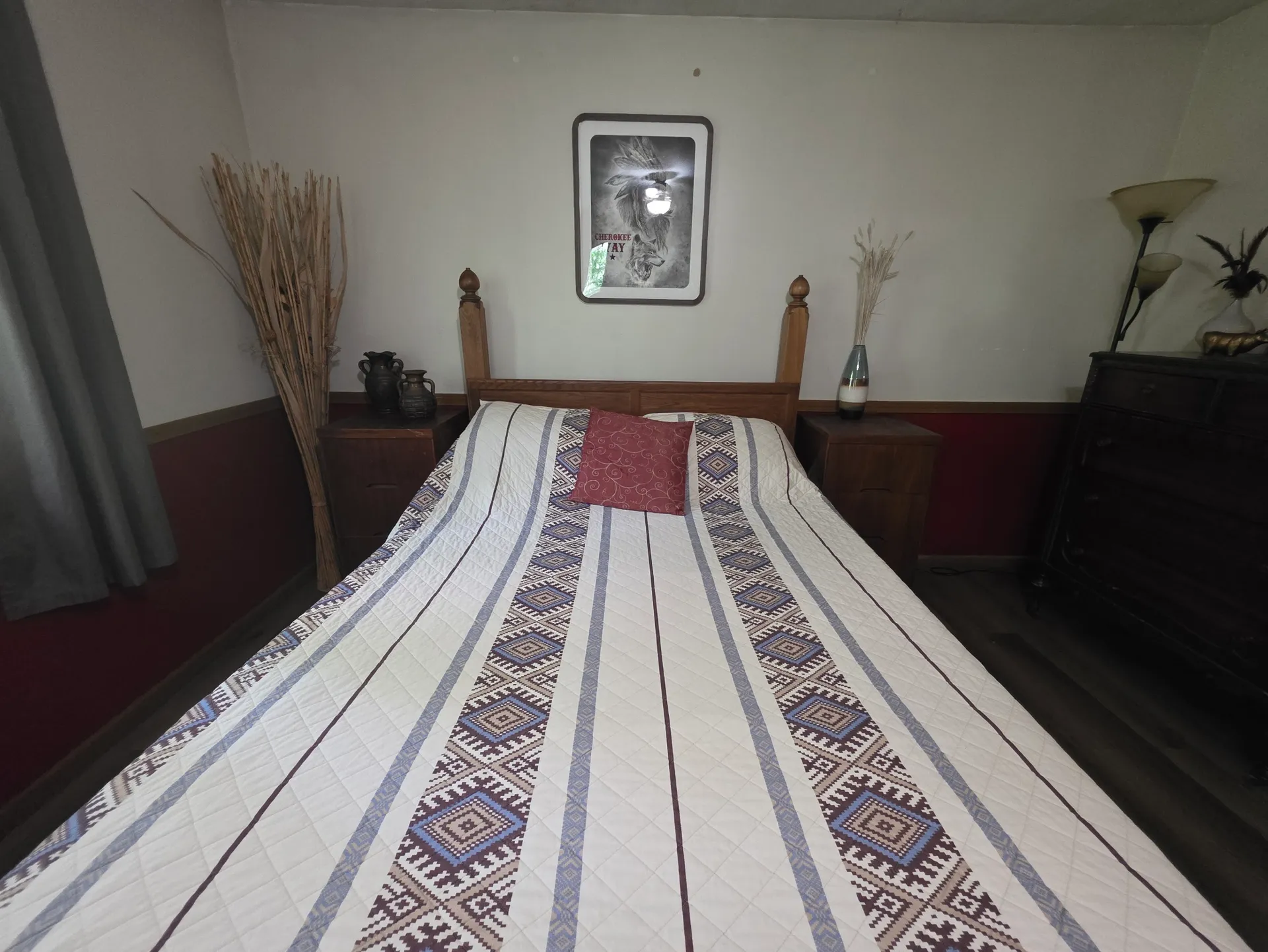 Main bedroom with queen bed, Native American patterned bedspread, and framed artwork at Cherokee Way cabin