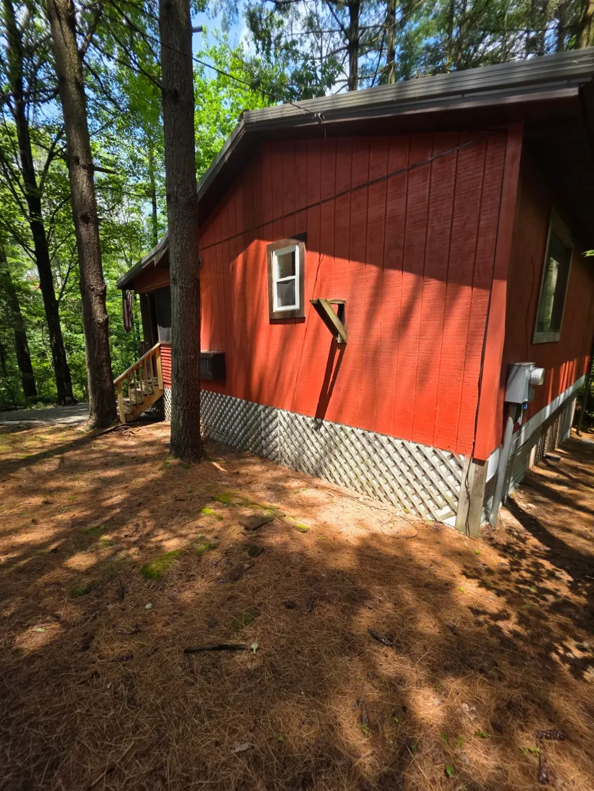 Back view of red Cherokee Way cabin showing roof and wooded hillside