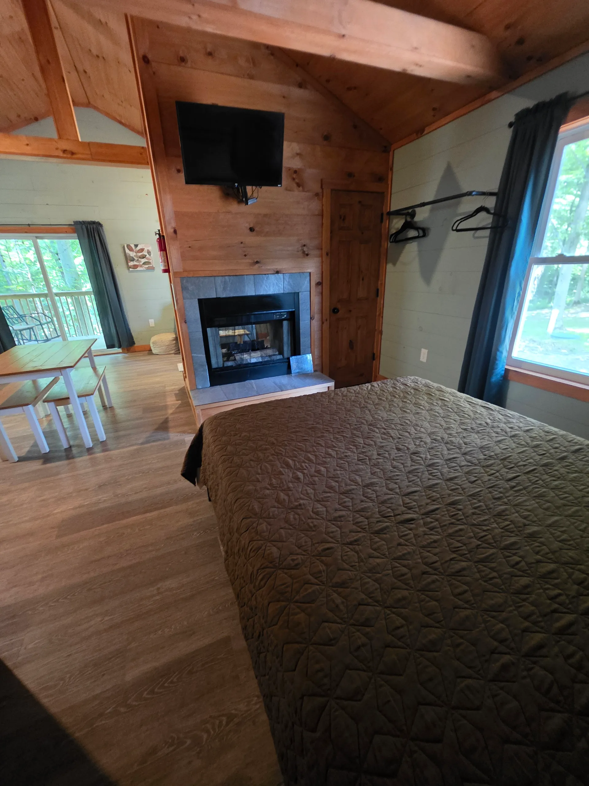 Bedroom and fireplace area with TV, wood paneling, and quilted bed at Dogwood Run cabin