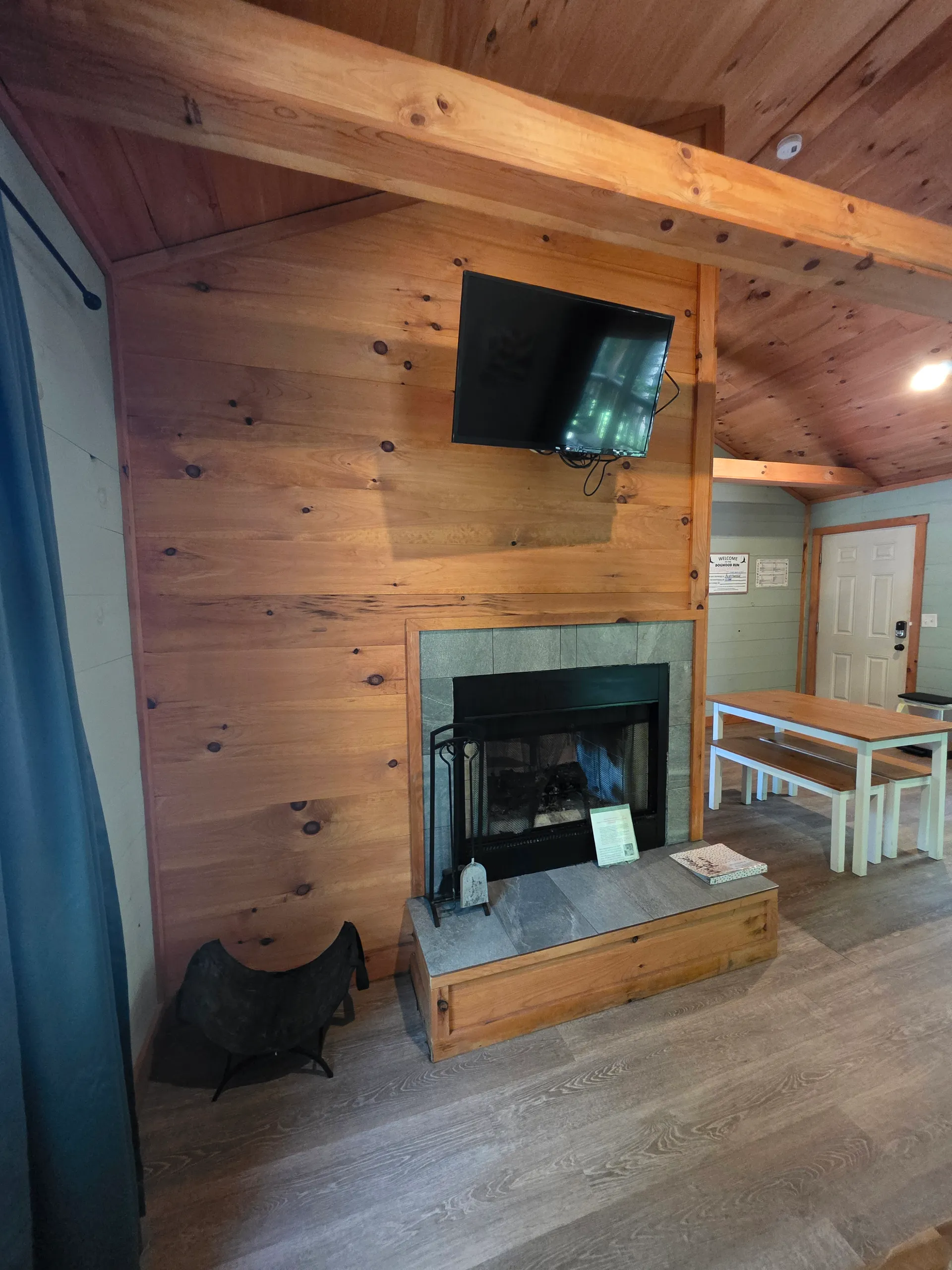 Wood fireplace wall close-up with TV, fire tools, and slate hearth at Dogwood Run cabin