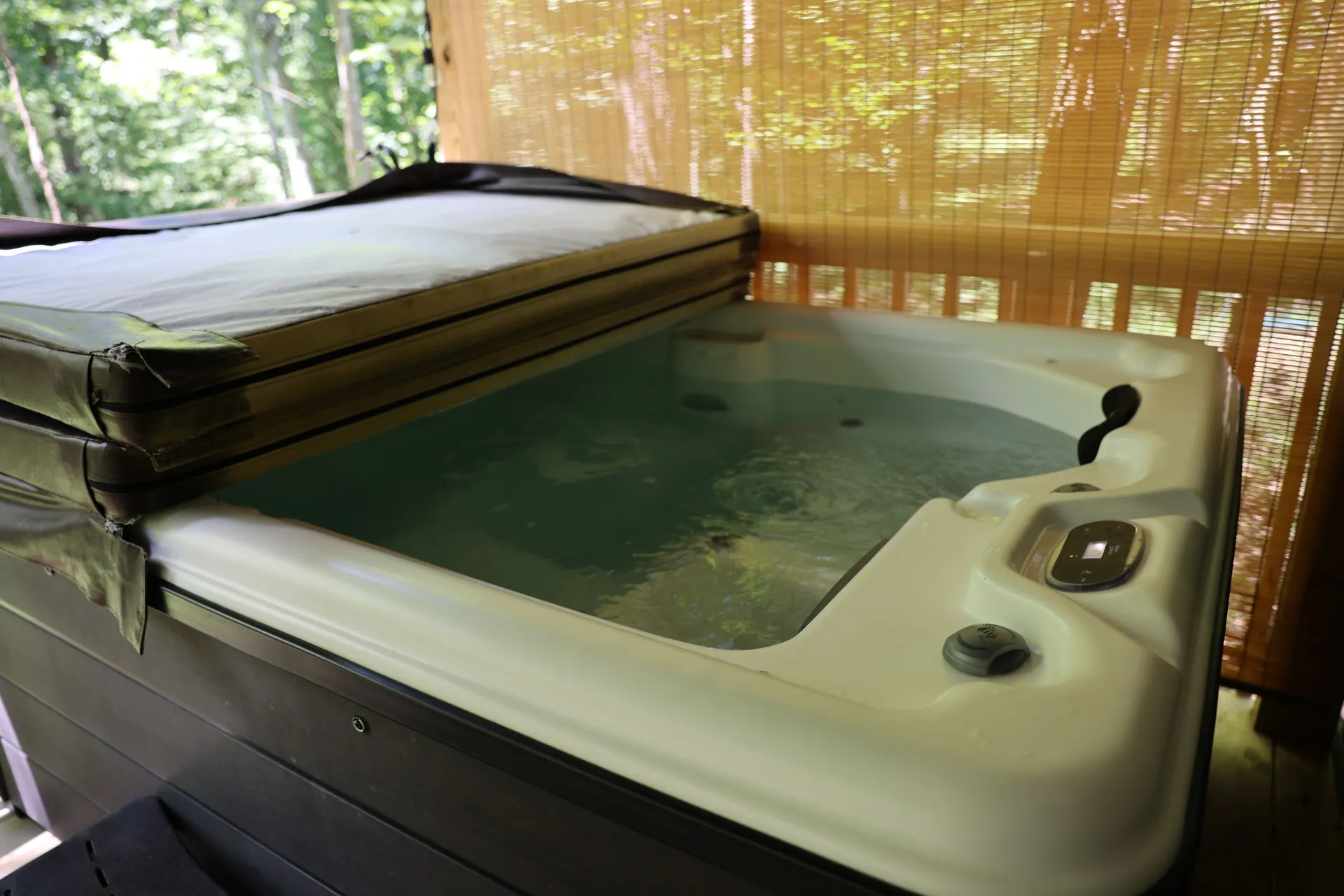 Open hot tub filled with water on the covered deck at Dogwood Run cabin