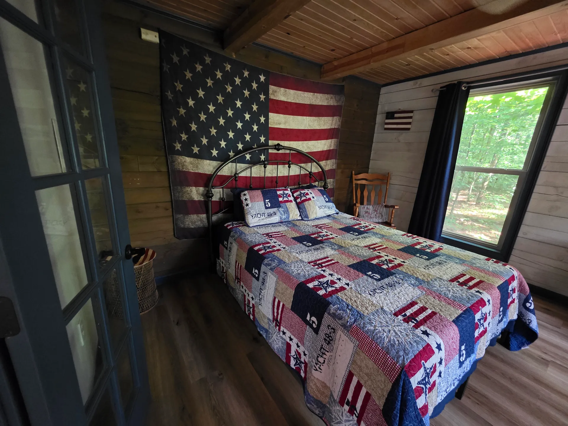 Cozy bedroom with queen bed, American flag headboard, and patchwork quilt in Eagles Nest cabin