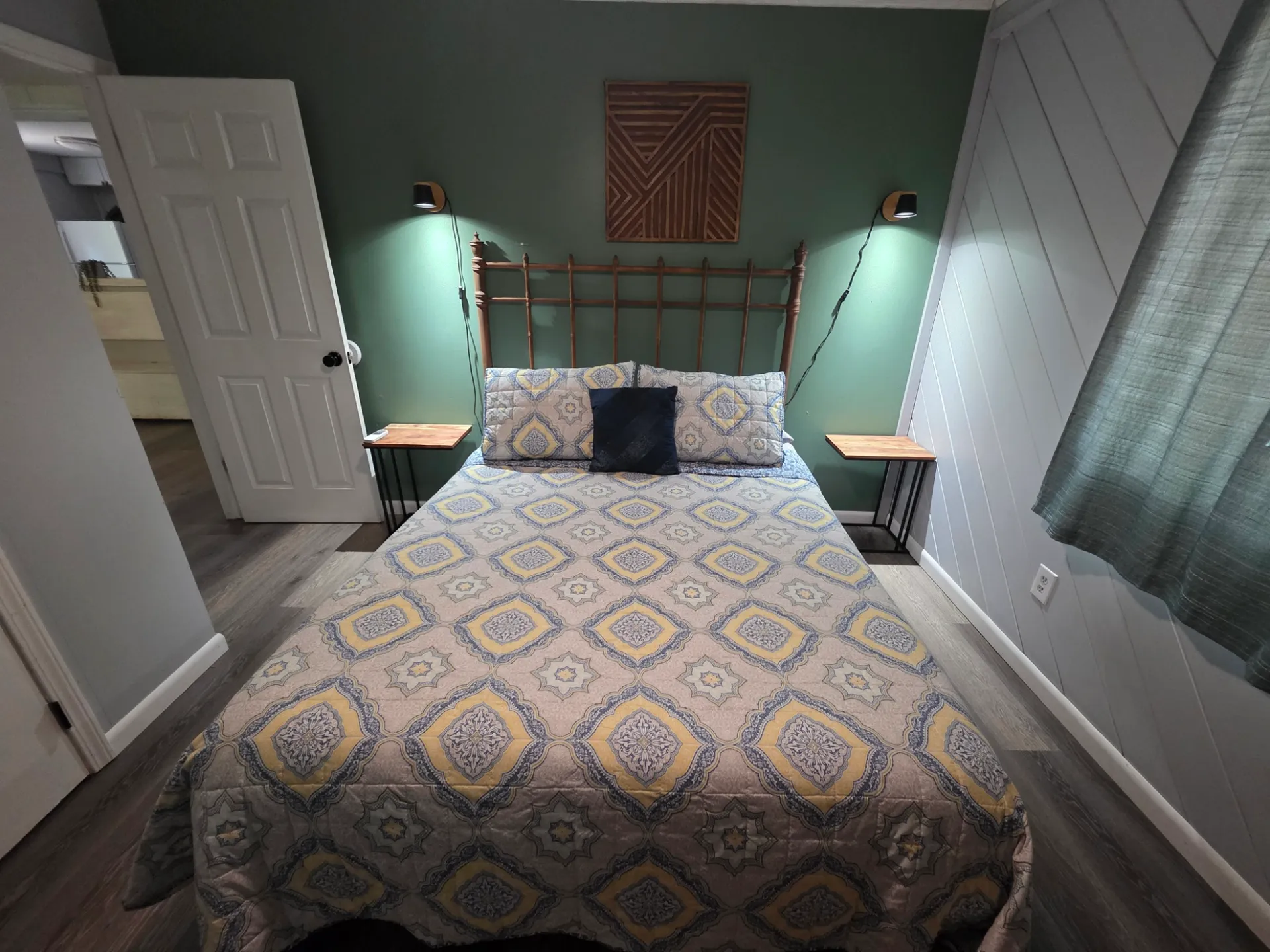 Queen bed with brass headboard, reading lights, and wooden wall art at Getaway House cabin