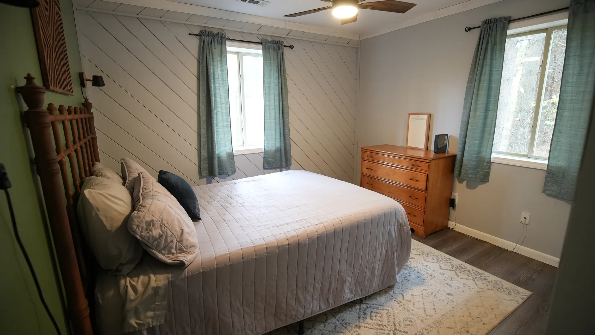 Spacious bedroom with queen bed, shiplap accent wall, dresser, and natural light at Getaway House cabin