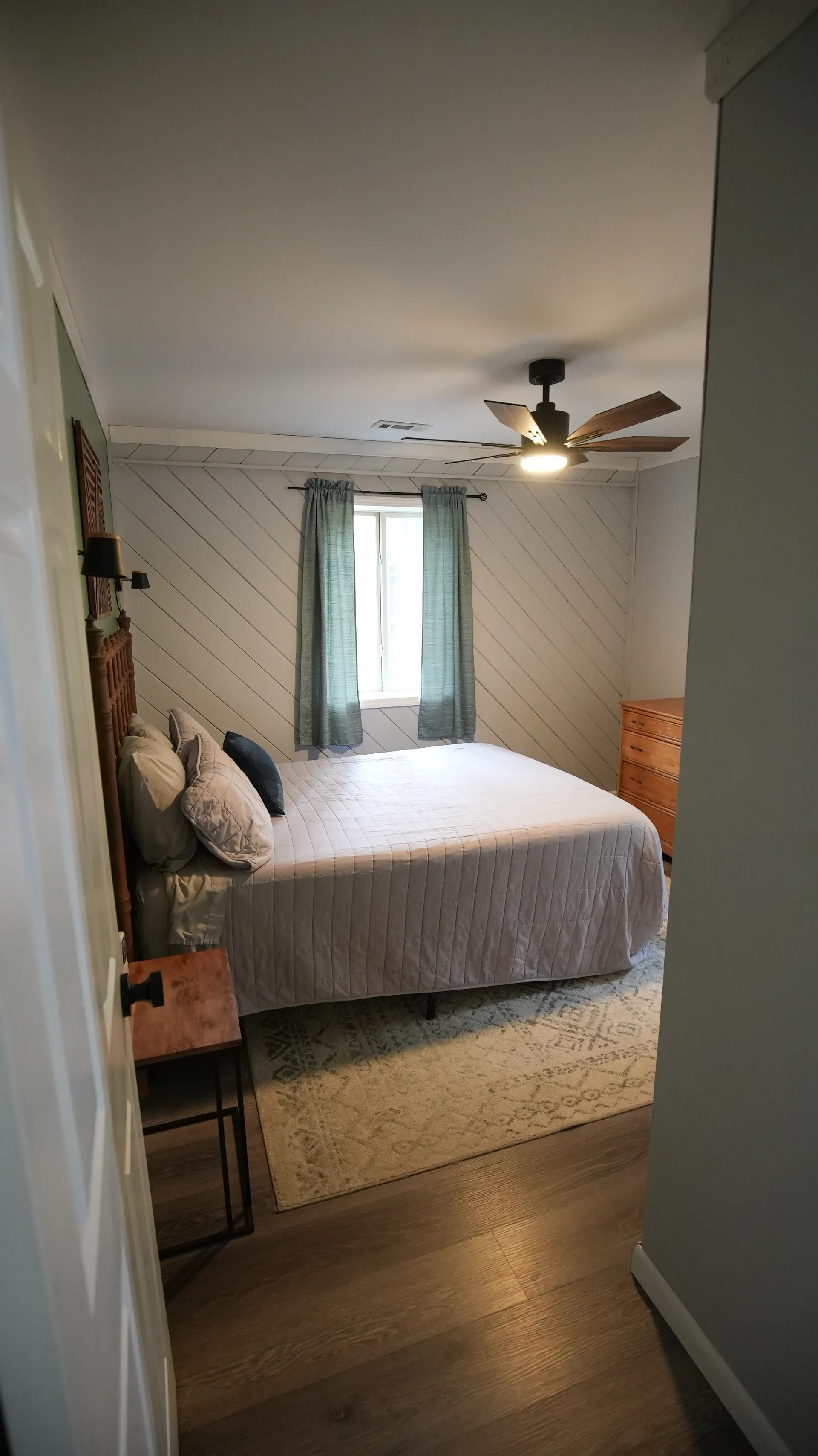 Bedroom with queen bed, shiplap accent wall, barn door, and ceiling fan at Getaway House cabin