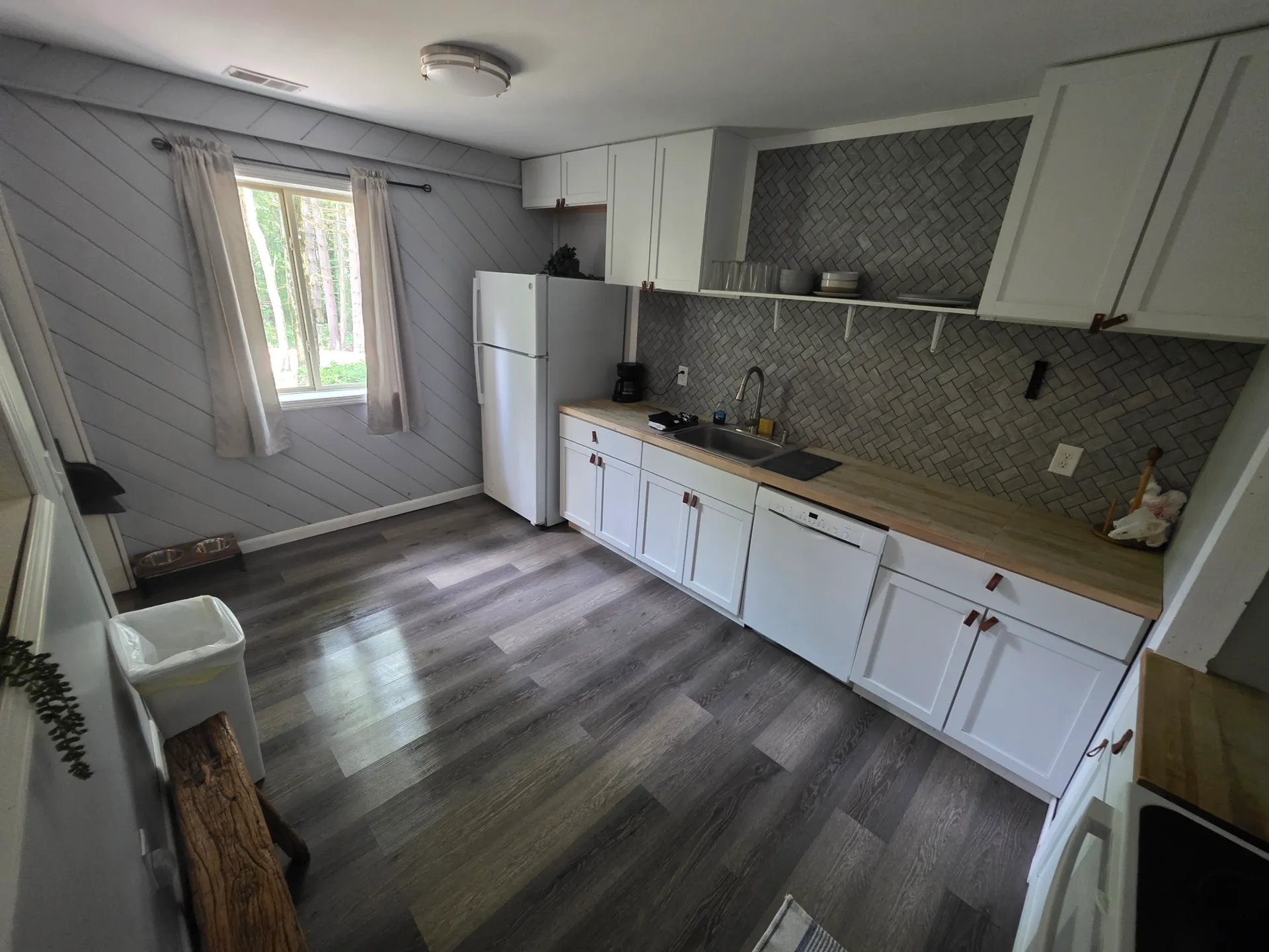 Spacious kitchen with shiplap walls, herringbone backsplash, and forest view window at Getaway House cabin