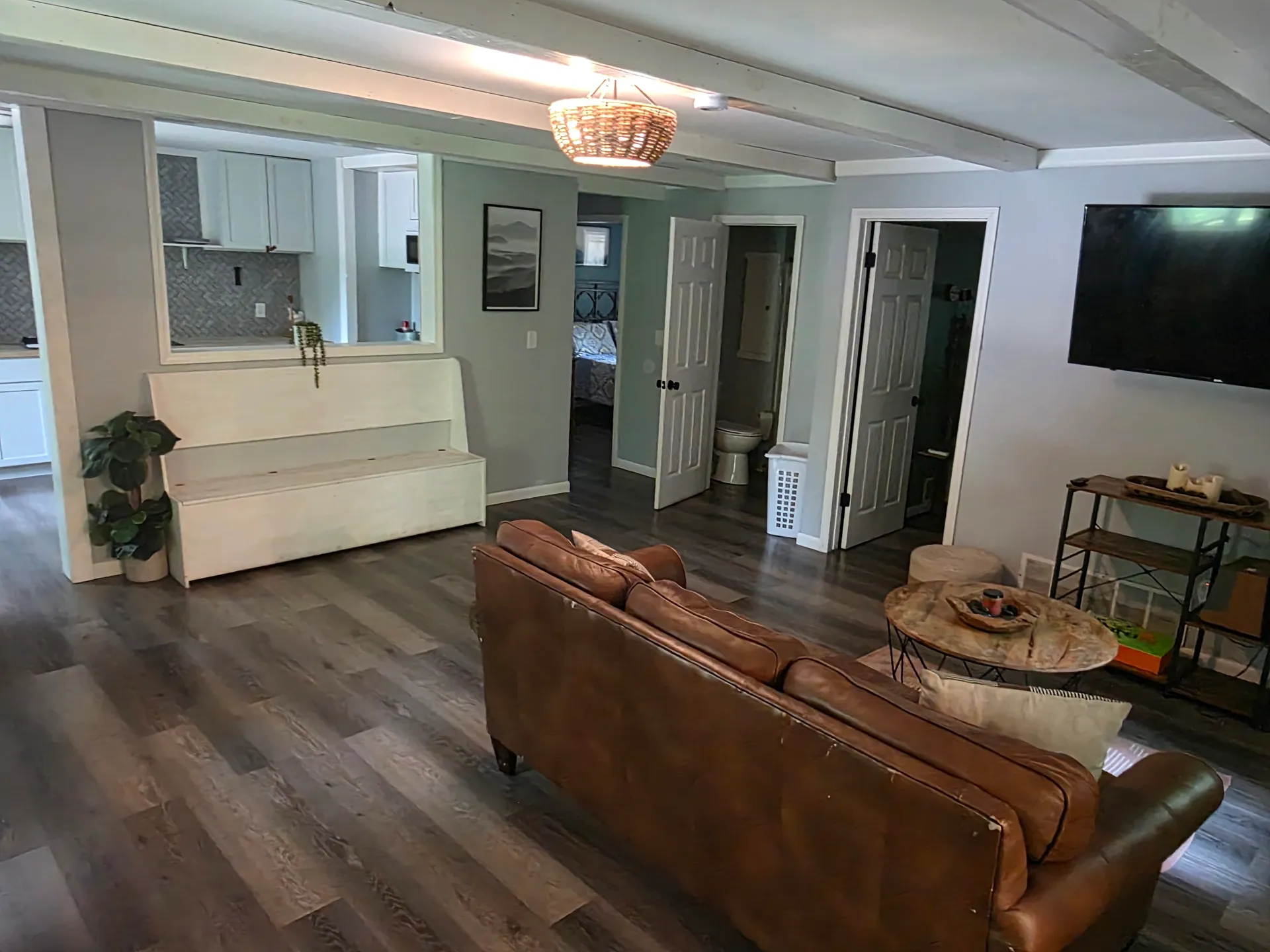 Living room with leather sofa, wall-mounted TV, and open views to kitchen and bedroom at Getaway House cabin