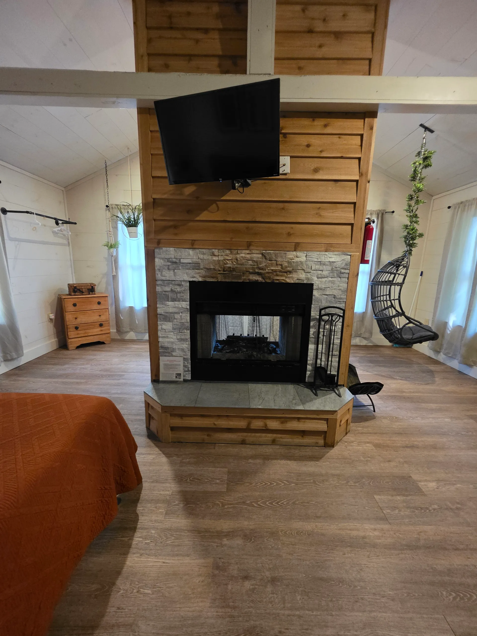 Cedar fireplace surround with stone accent, mounted TV, and warm lighting at Hummingbird cabin