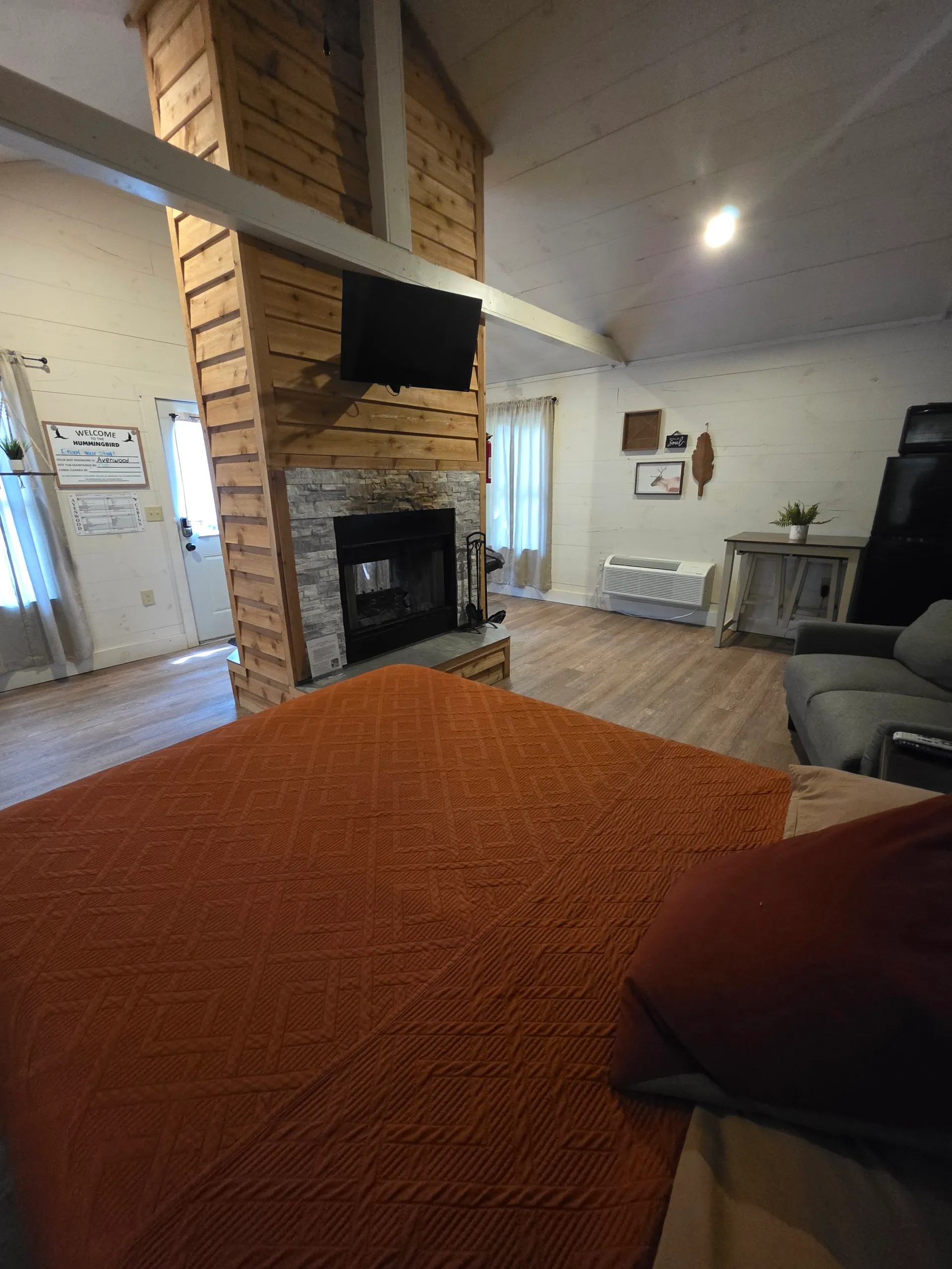 Wide view of the bedroom and fireplace with warm lighting at Hummingbird cabin