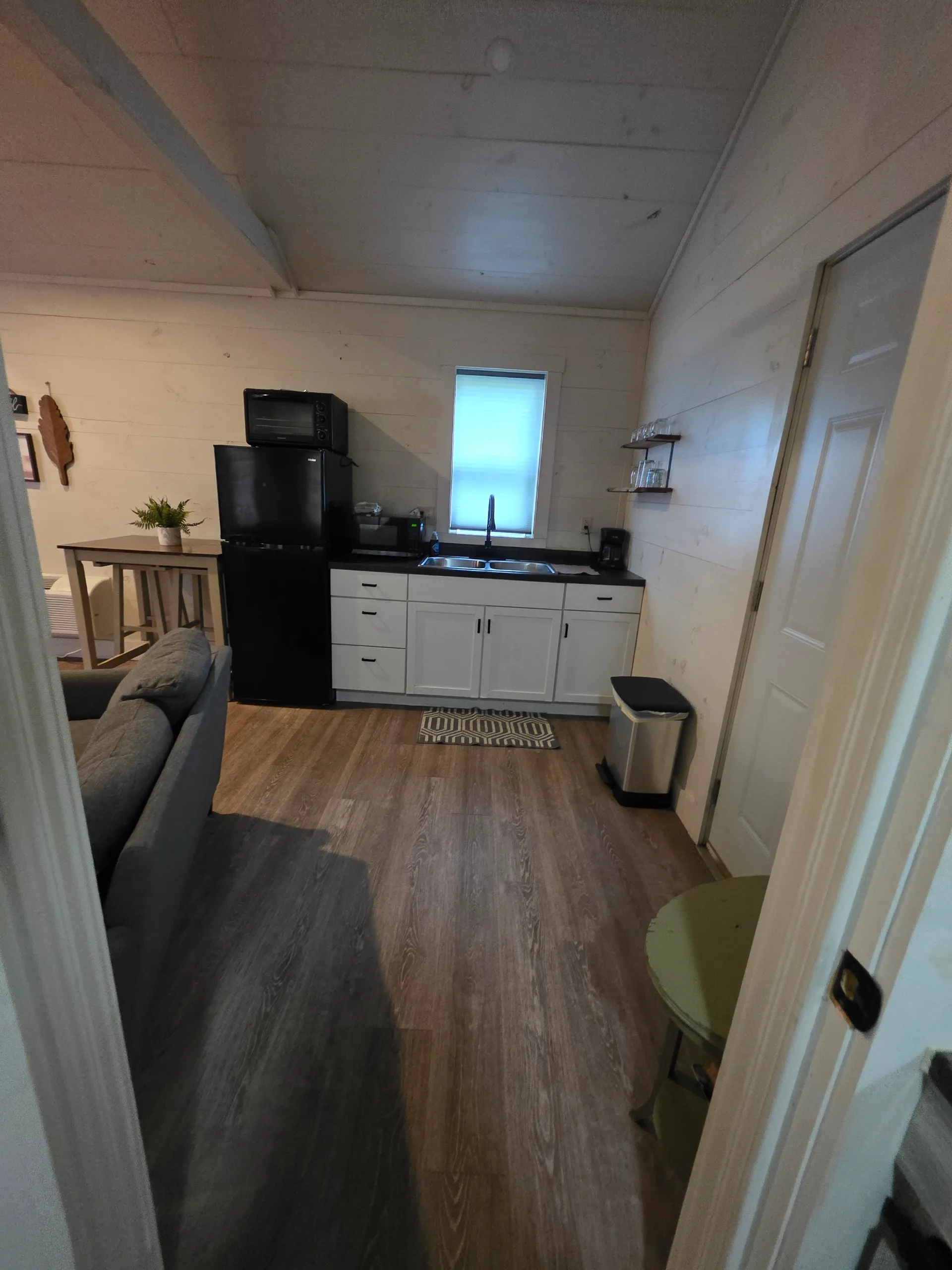 Full kitchenette with white cabinets, black fridge, microwave, and mounted TV at Hummingbird cabin
