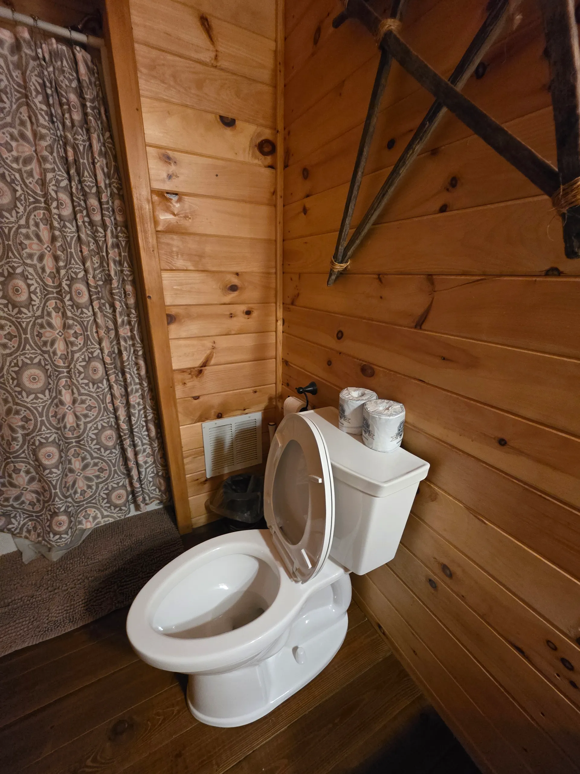 Pine-paneled bathroom with patterned tile floor at Millers Den cabin