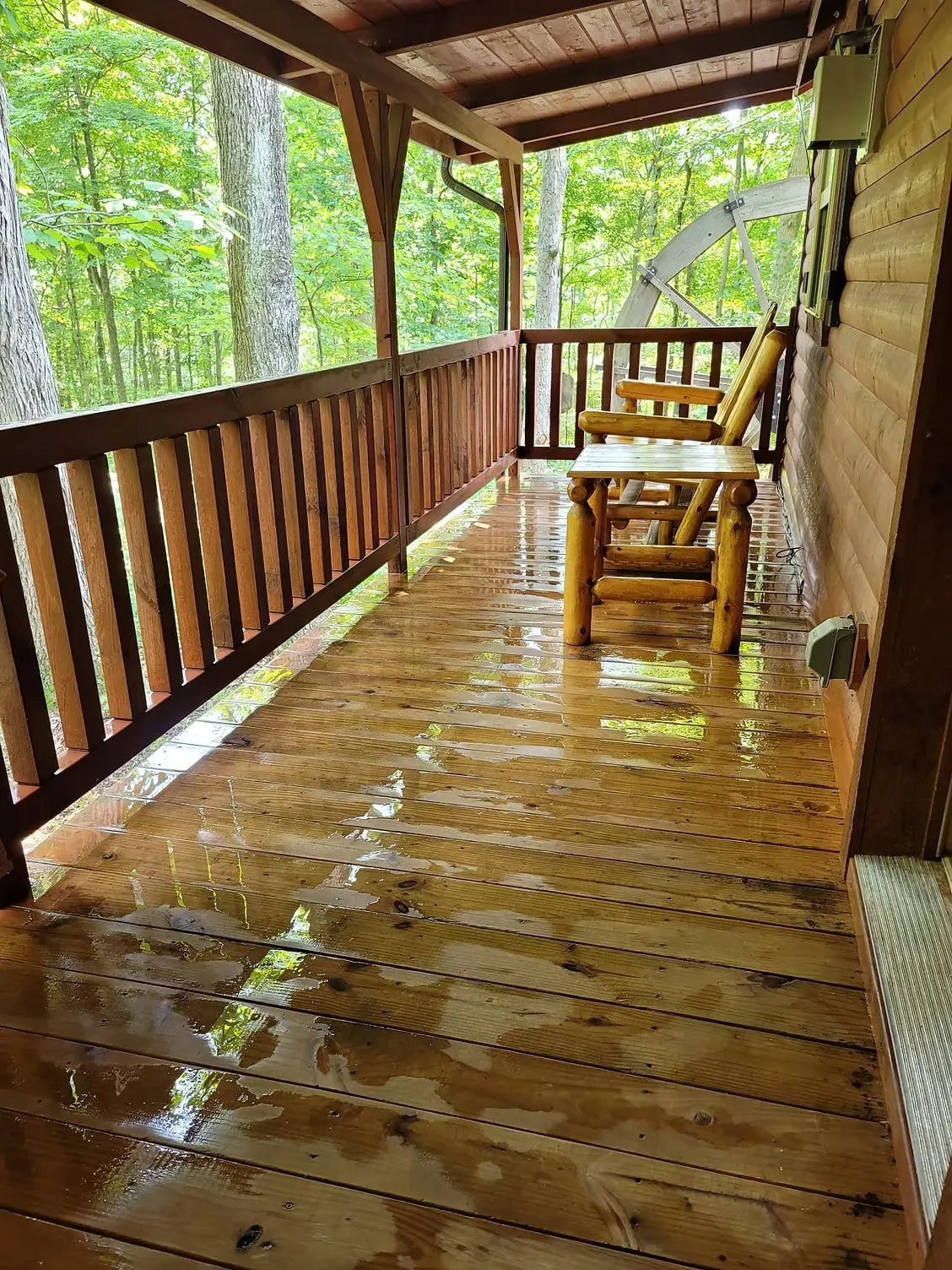 Rain-soaked covered porch with log rocking chair at Millers Den cabin in Hocking Hills