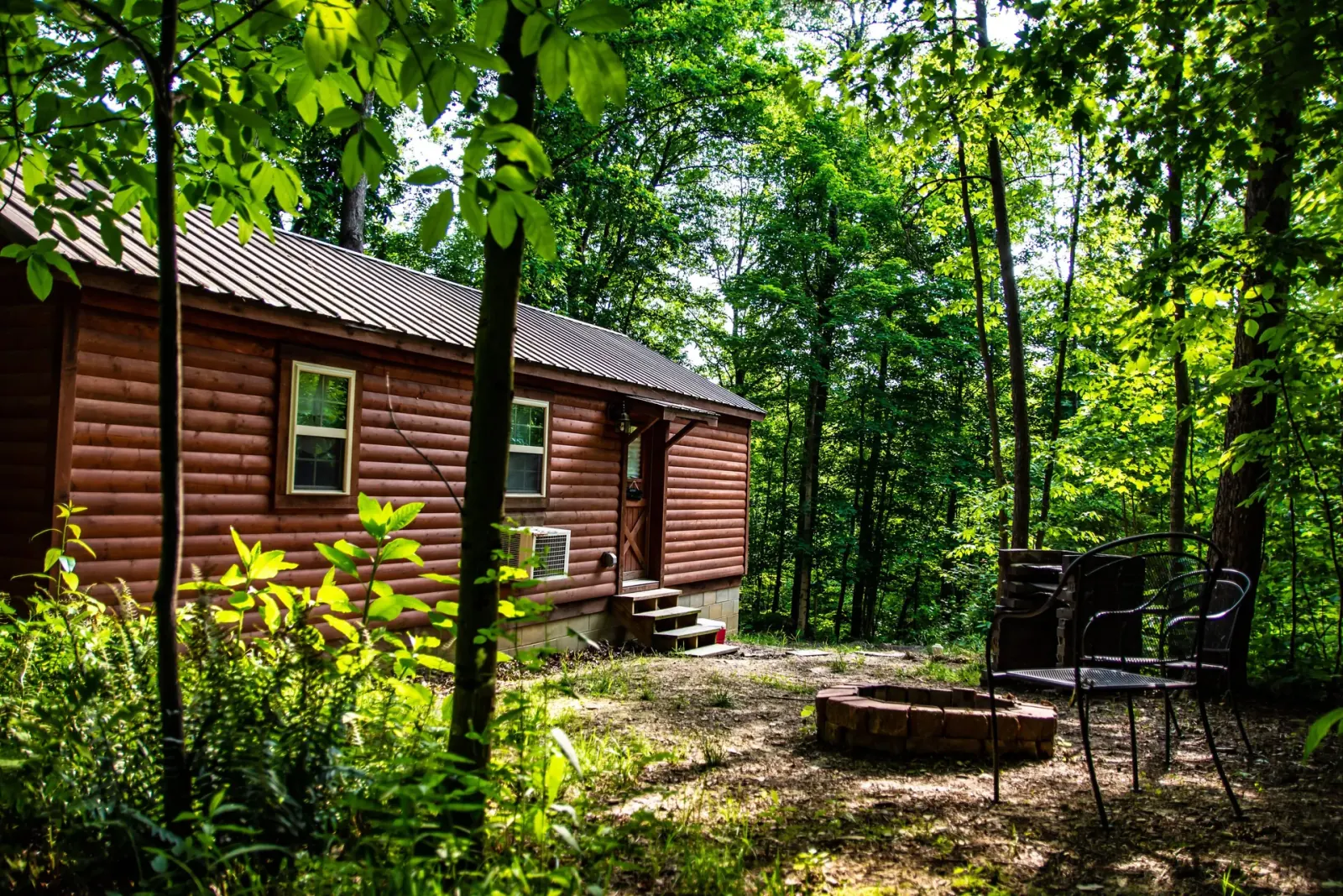 Millers Den log cabin exterior with stone fire pit and patio chairs in Hocking Hills
