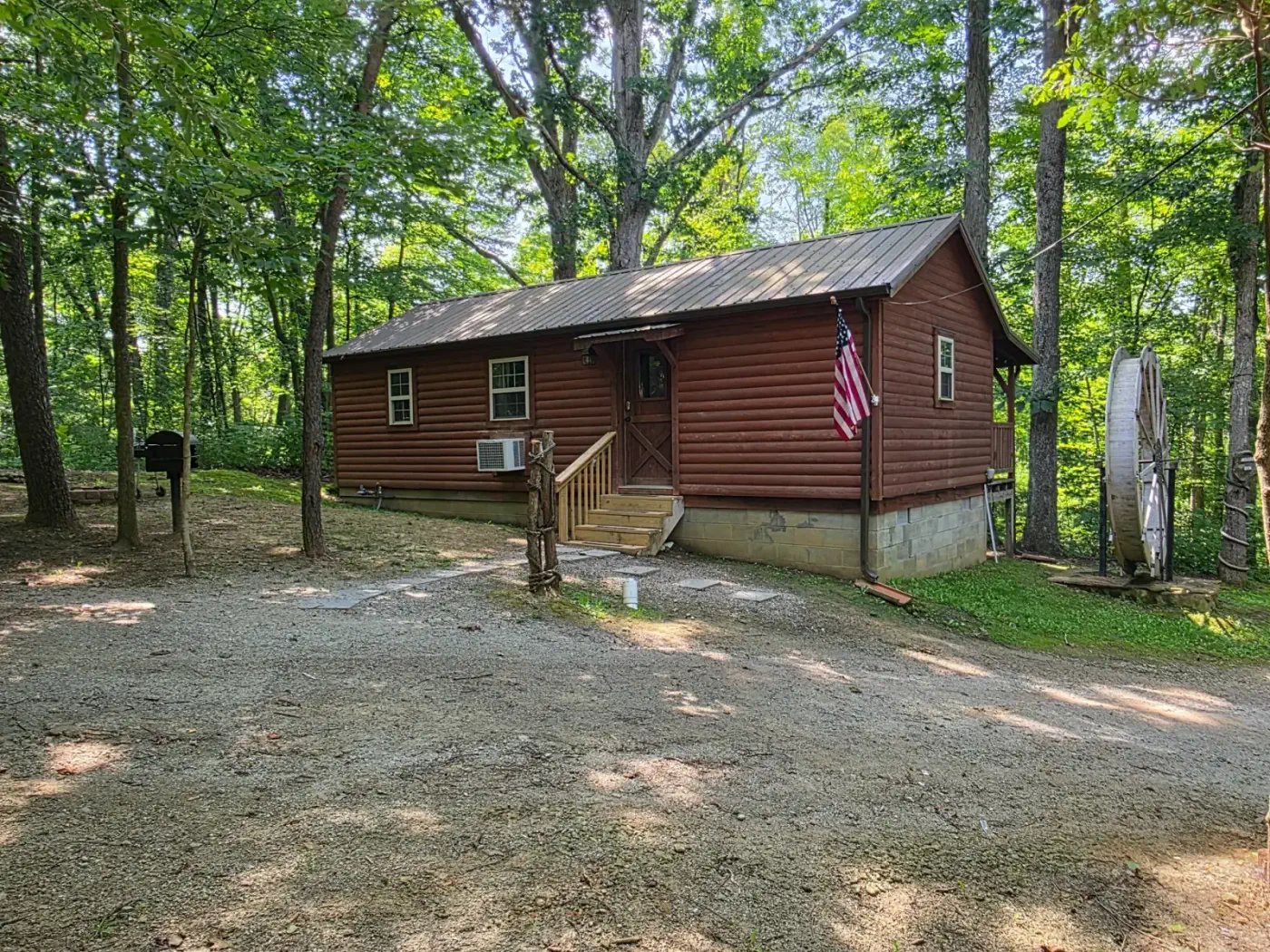 Front view of Millers Den log cabin with American flag in wooded Hocking Hills setting