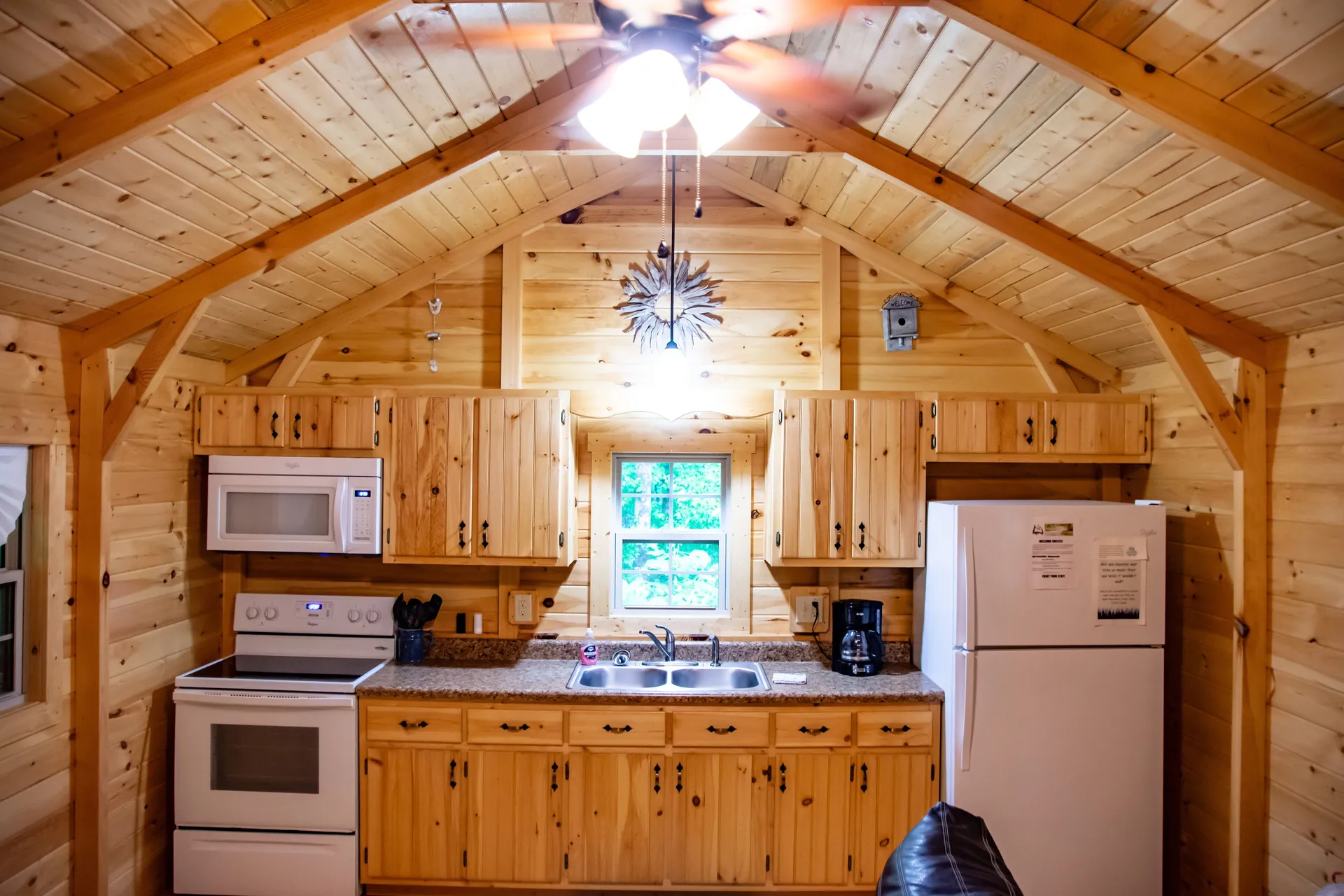 Kitchen with pine cabinets, full appliances, and vaulted timber ceiling at Millers Den cabin