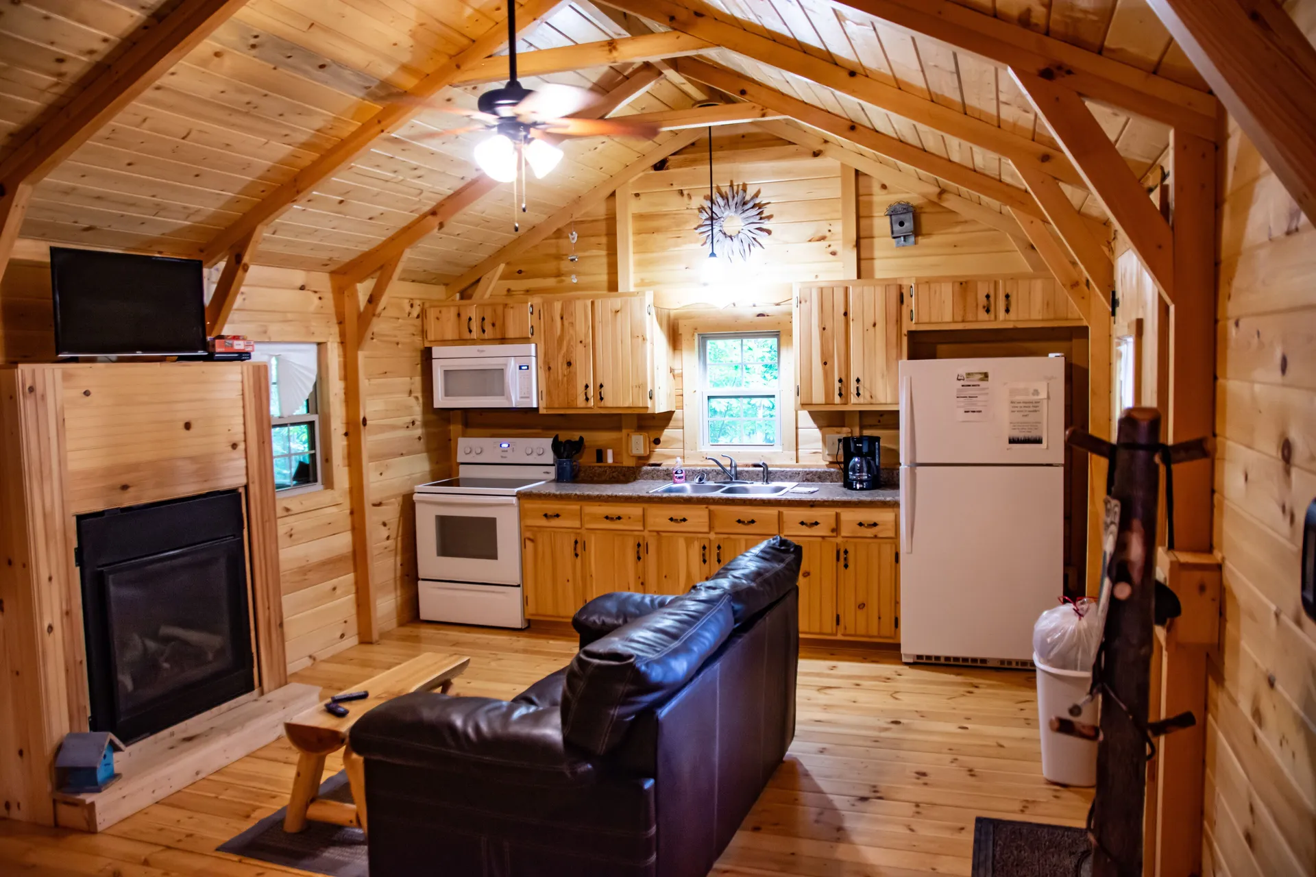 Open floor plan showing full kitchen, leather sofa, and fireplace at Millers Den cabin