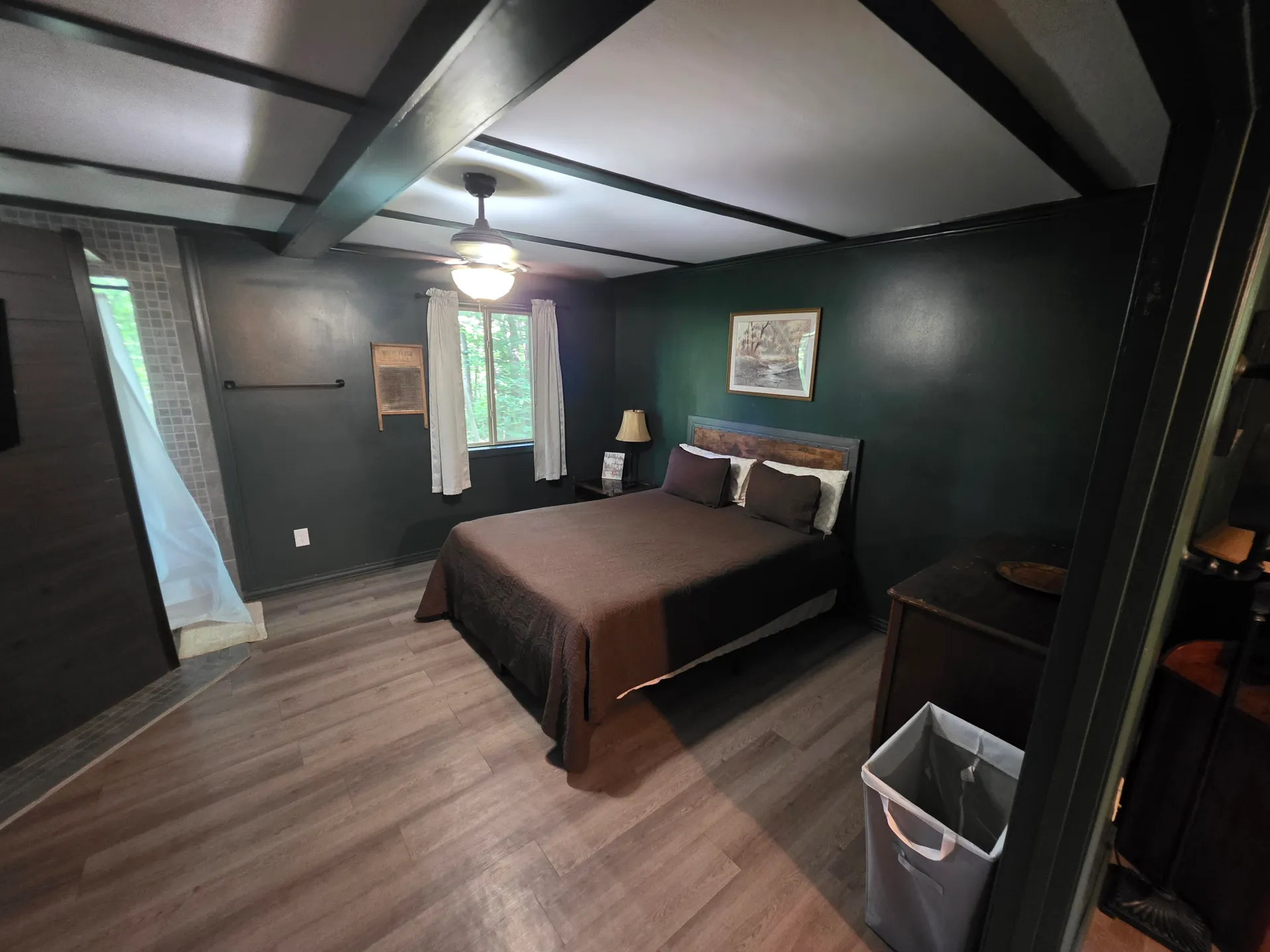 Moody green bedroom with queen bed, rustic headboard, and ceiling fan at Moonshiner cabin