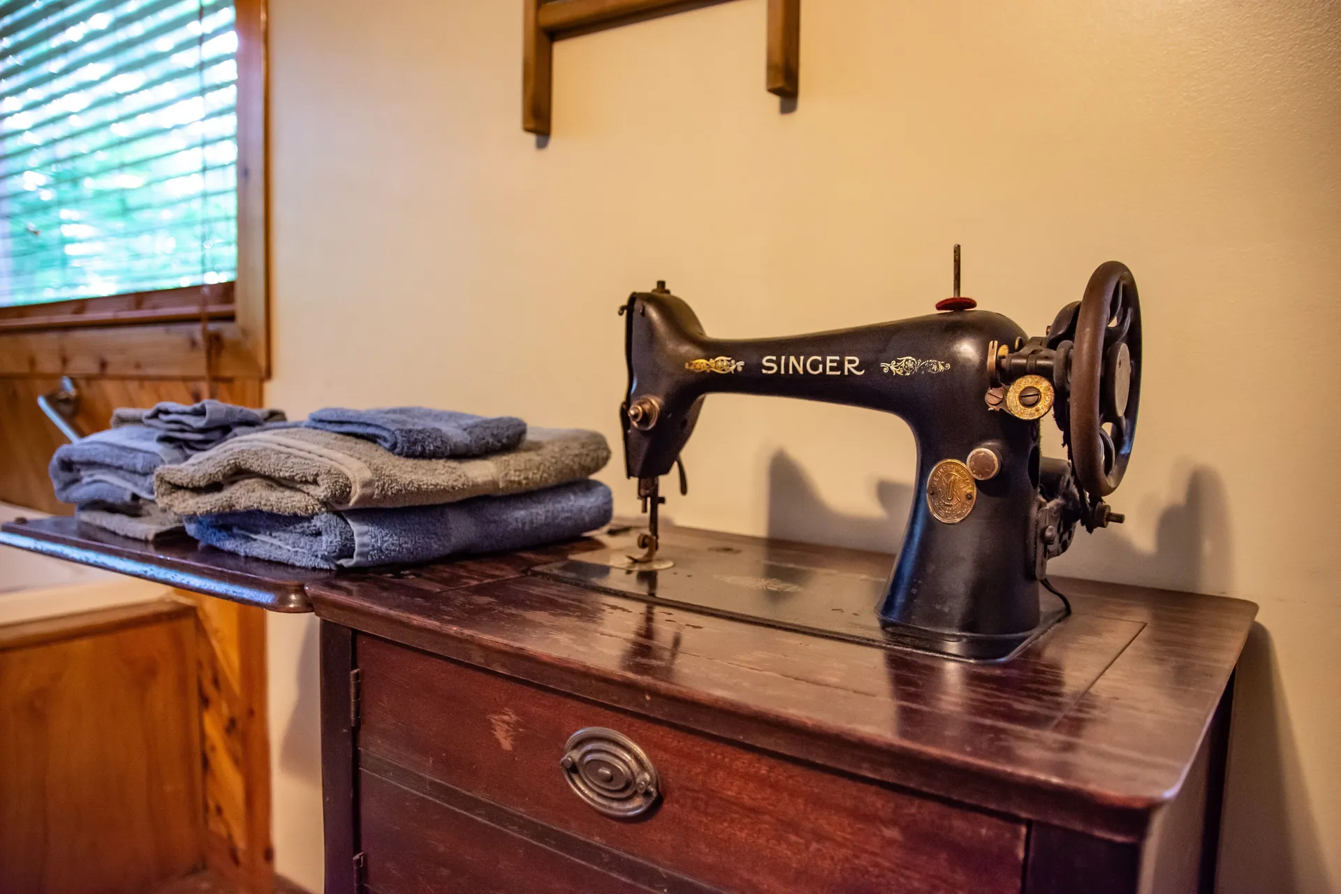 Vintage Singer sewing machine with folded towels as rustic decor at Moonshiner cabin