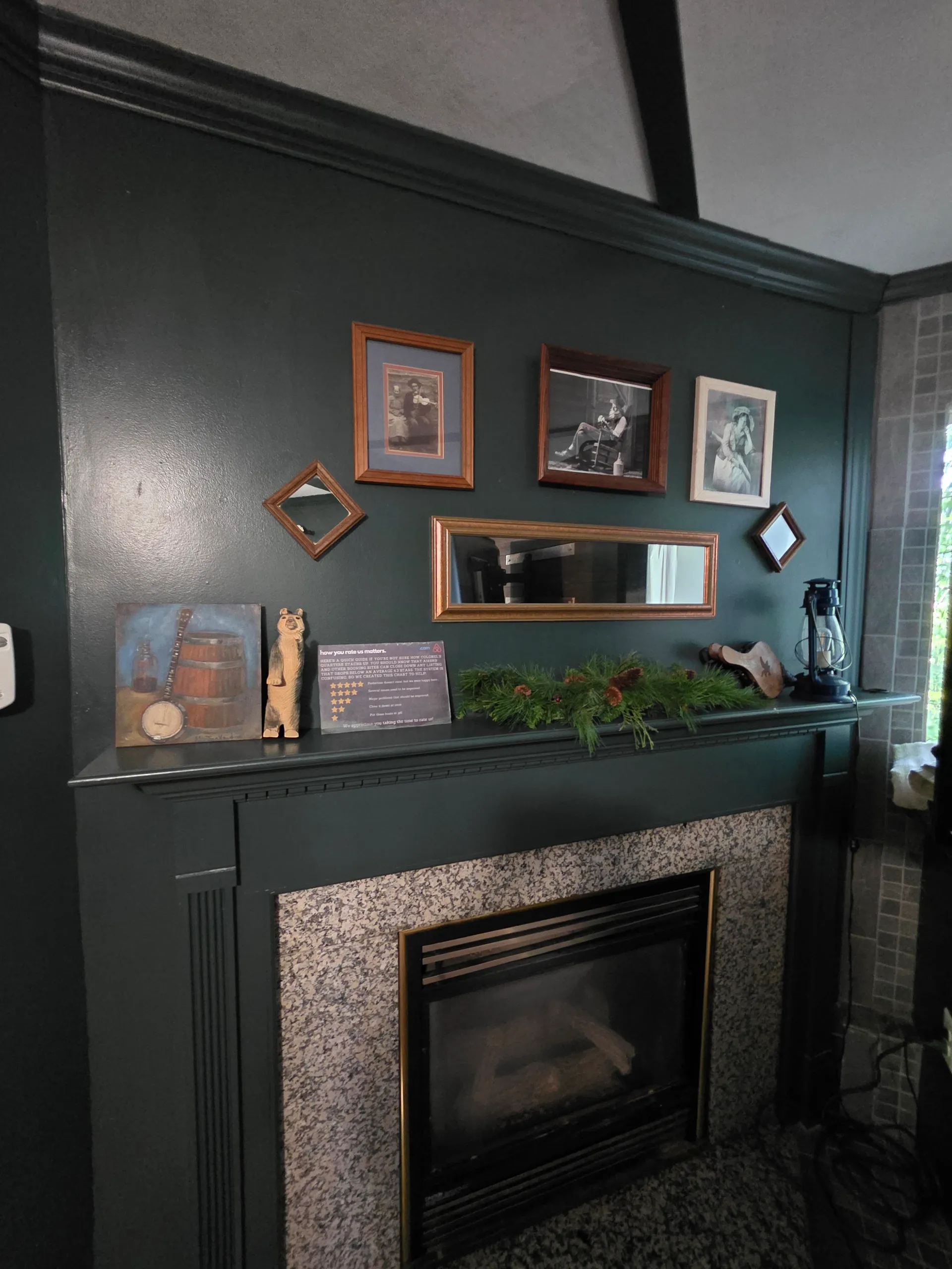 Fireplace with granite surround and vintage photo gallery wall on dark green walls at Moonshiner cabin