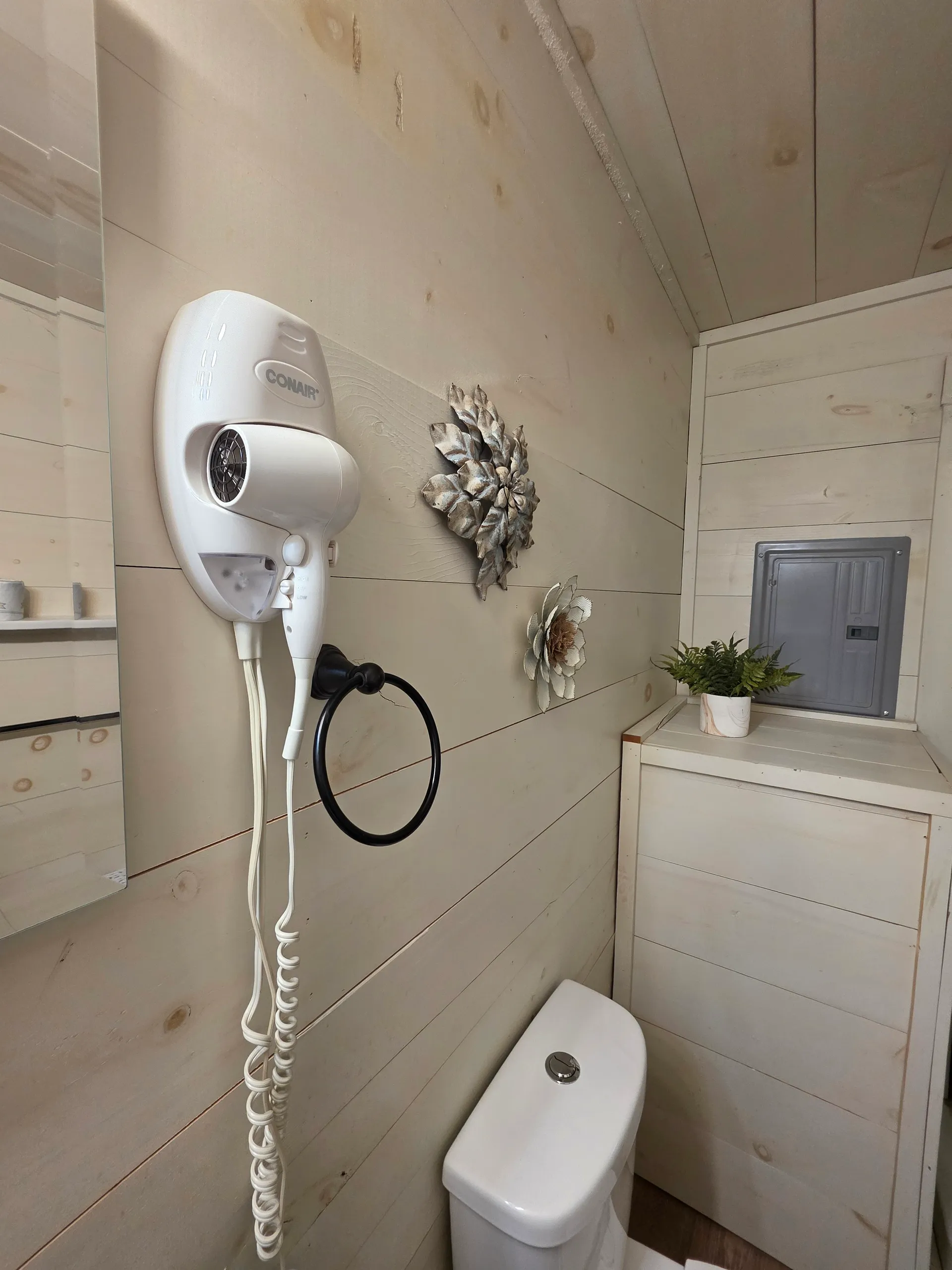 Bathroom amenities including hair dryer and decorative metal art on shiplap wall at Owl's Tale cabin