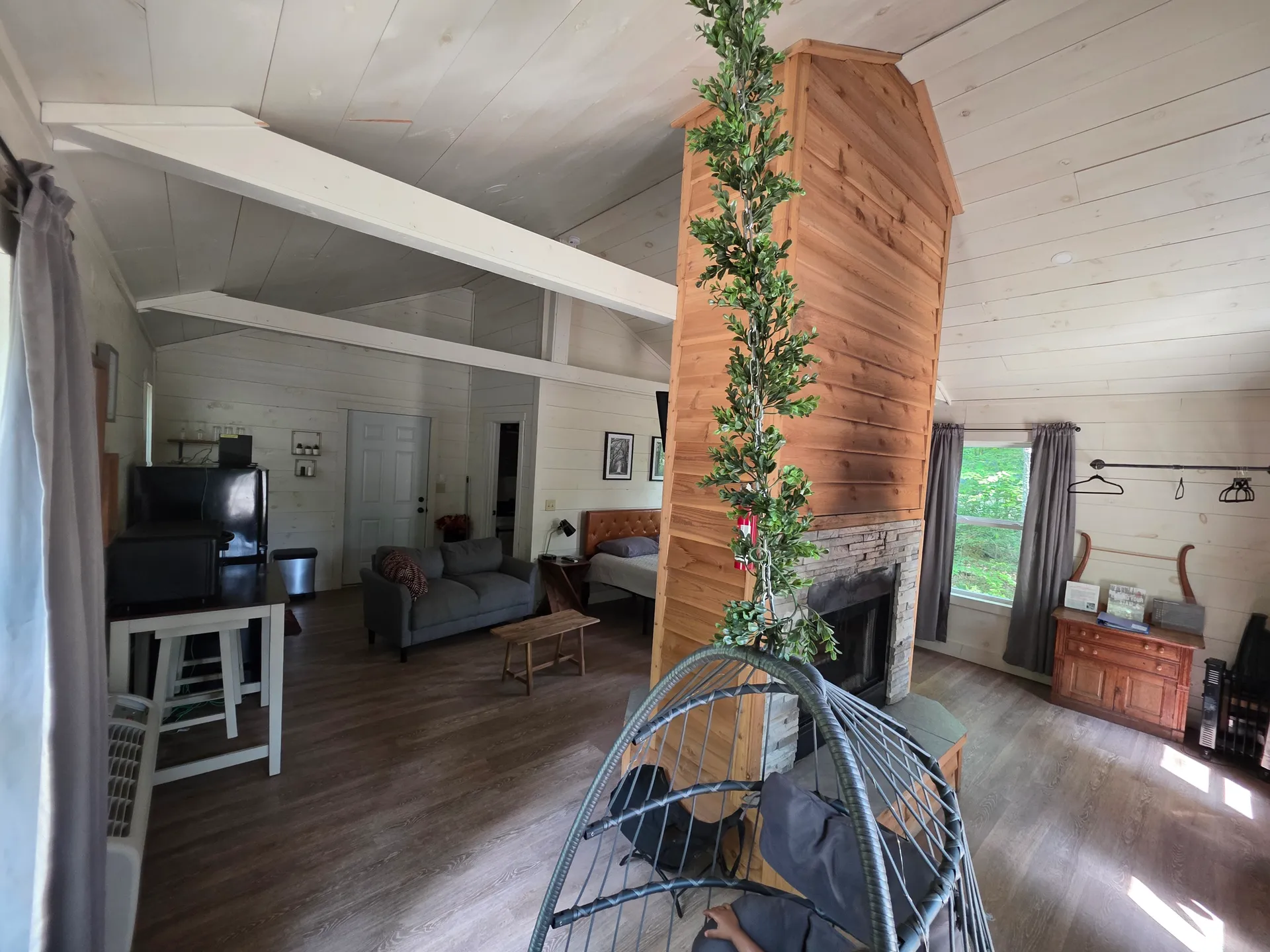 Interior view from the hanging egg chair showing the fireplace, kitchen, and living area at Owl's Tale cabin