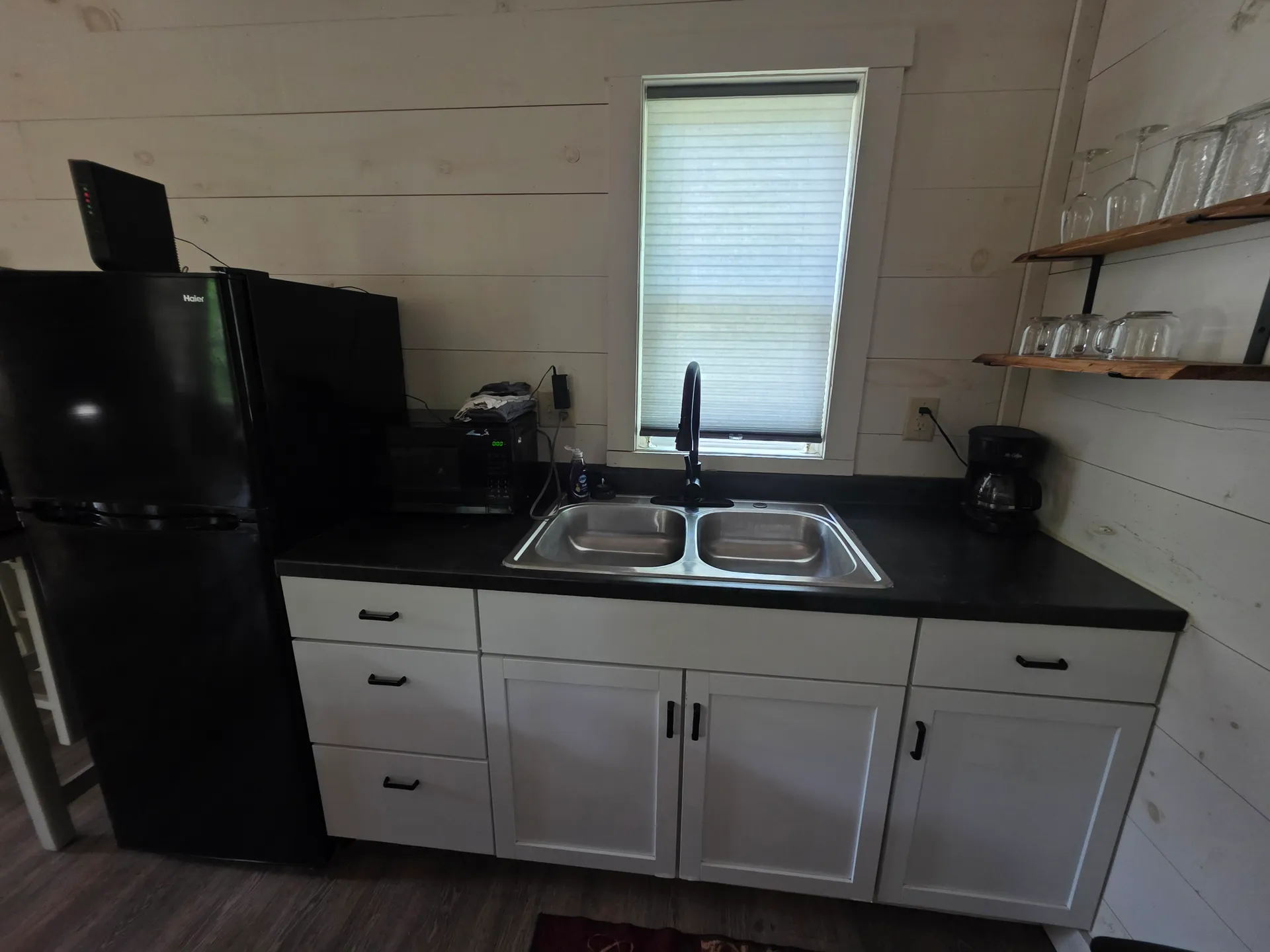 Full kitchenette with white cabinets, black fridge, microwave, and double sink at Owl's Tale cabin