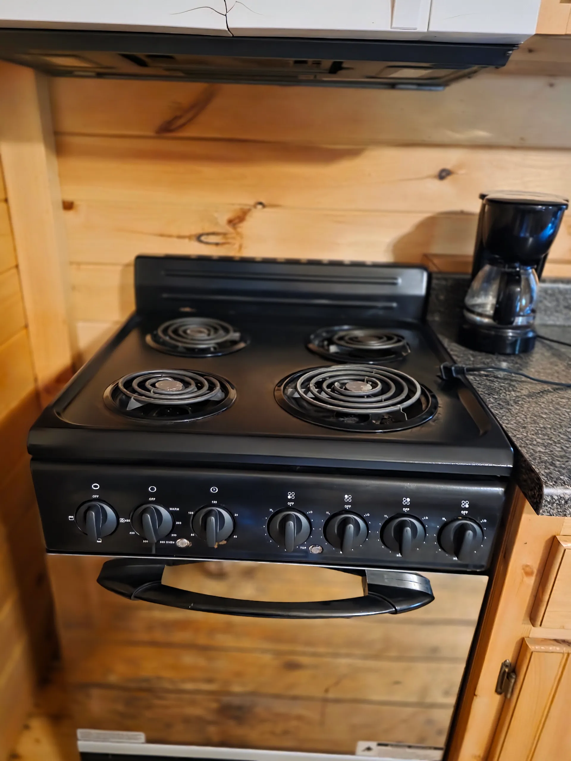 Black electric stove and oven in the pine kitchen of Settlers Roost cabin