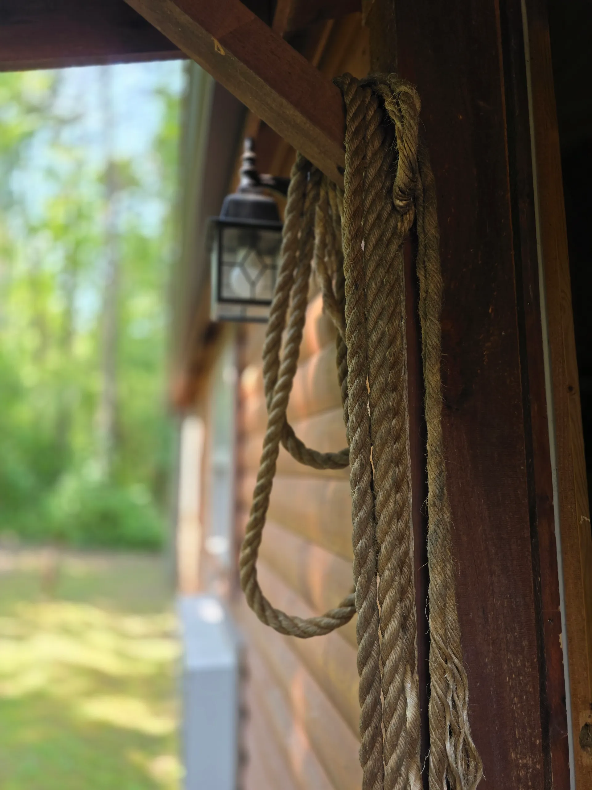 Rustic rope railing detail on the covered porch of Settlers Roost cabin
