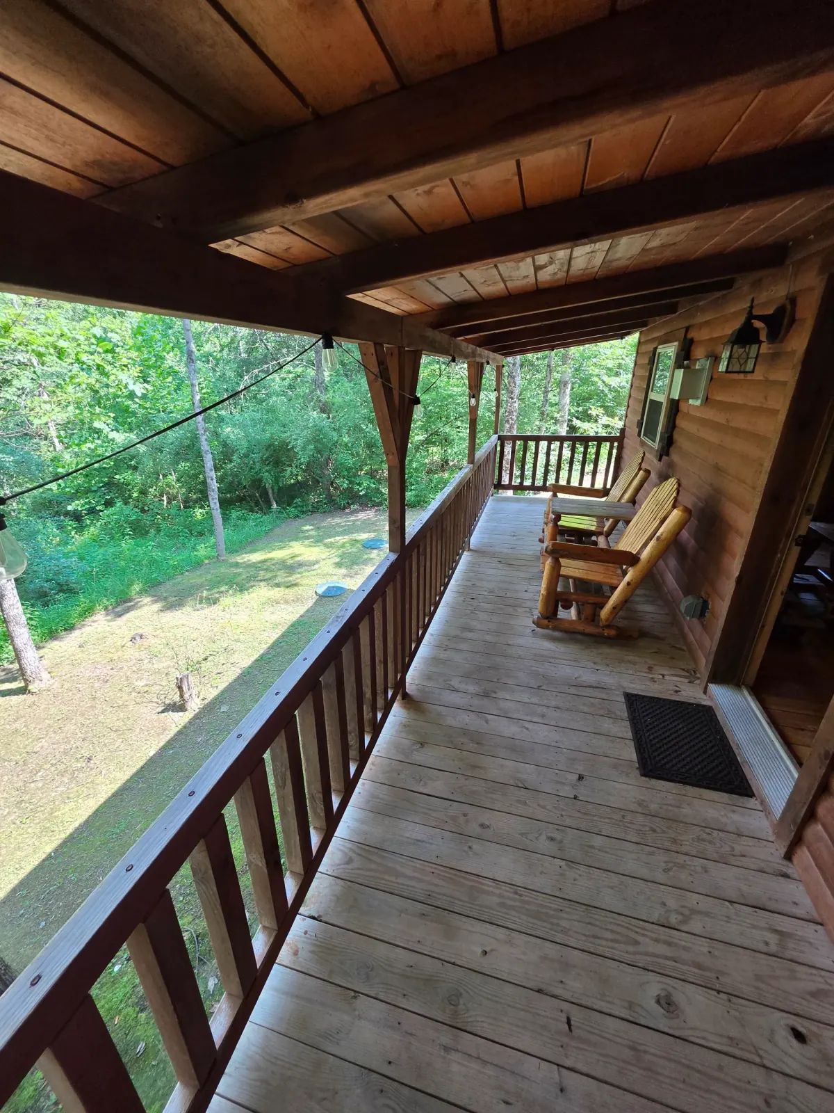 Wraparound wooden deck with railing and forest views at Settlers Roost cabin in Hocking Hills